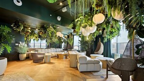A modern interior with a wooden floor, white sofas, hanging plants, and a view of the city. - The YORK suite Miami downtown (Miami)
