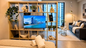 A modern living room with a large flat-screen TV, a wooden entertainment unit with books and decorative items, a sofa, and a coffee table. - The YORK suite Miami downtown (Miami)