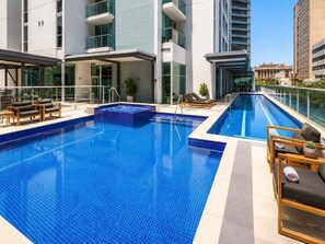 A rooftop pool with lounge chairs and a glass balustrade. - Brisbane CBD Skyline Stay + Resort Amenities (Brisbane)