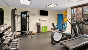 Une salle de sport équipée de tapis de course, d’appareils de musculation et de ballons d’exercice.