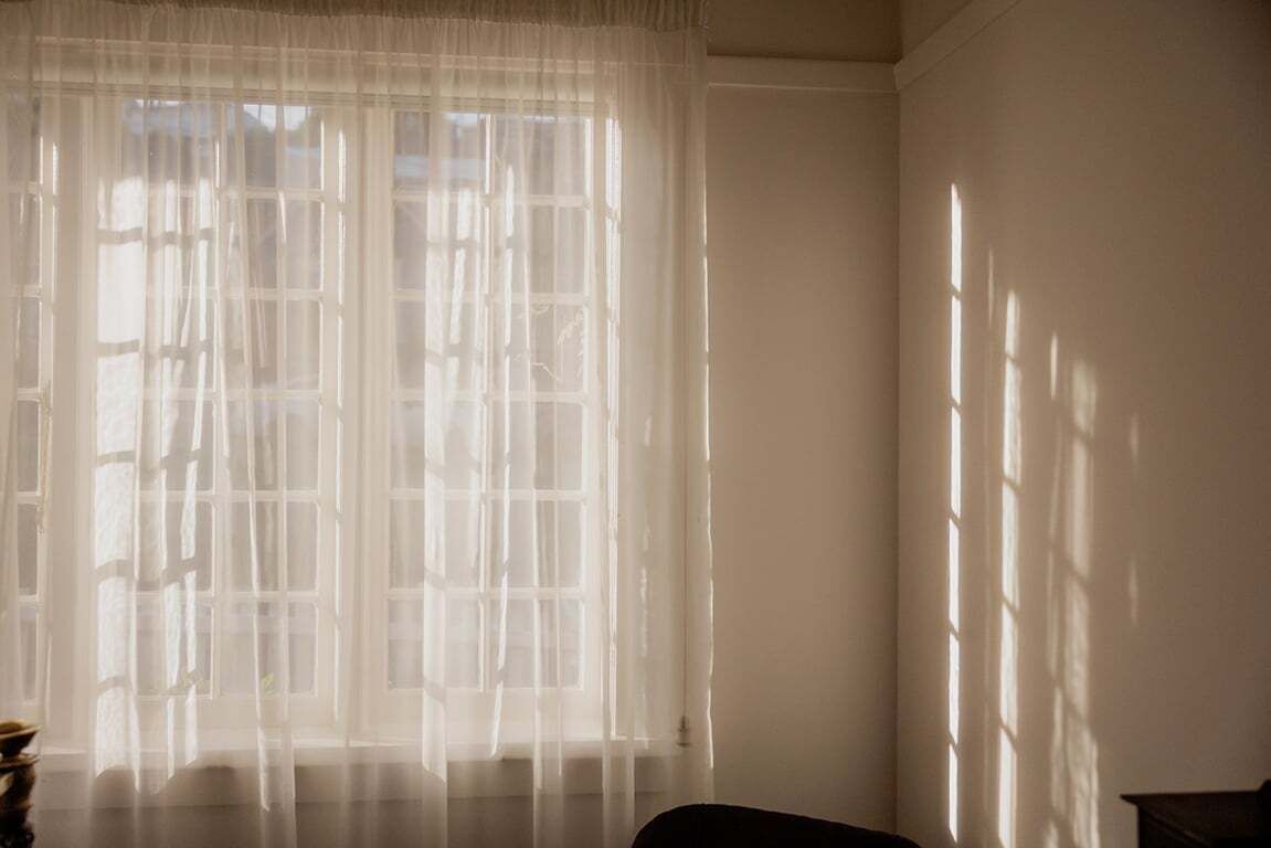 A room with a large window covered by sheer curtains, allowing natural light to enter.