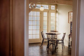Ein Zimmer mit einem runden Tisch und vier Stühlen, einem Fenster mit satinierten Glasscheiben und einer Hängelampe.