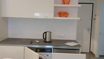 Een koelkast, een oven, een vaatwasser, kookgerei, borden en bestek