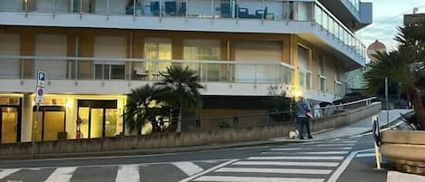 Un edificio de varios pisos con balcones, un paso de peatones y una calle.
