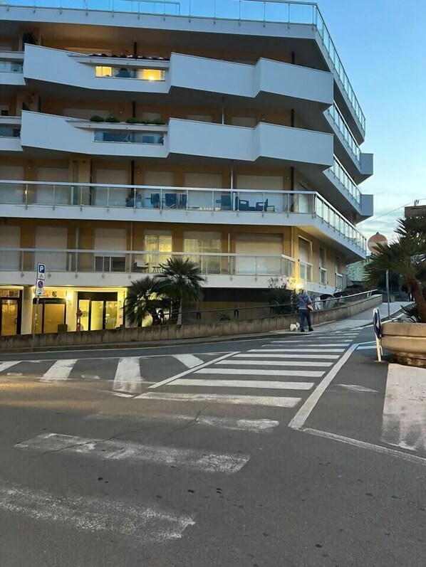 Un immeuble à plusieurs étages doté de balcons, un passage piéton et une rue.