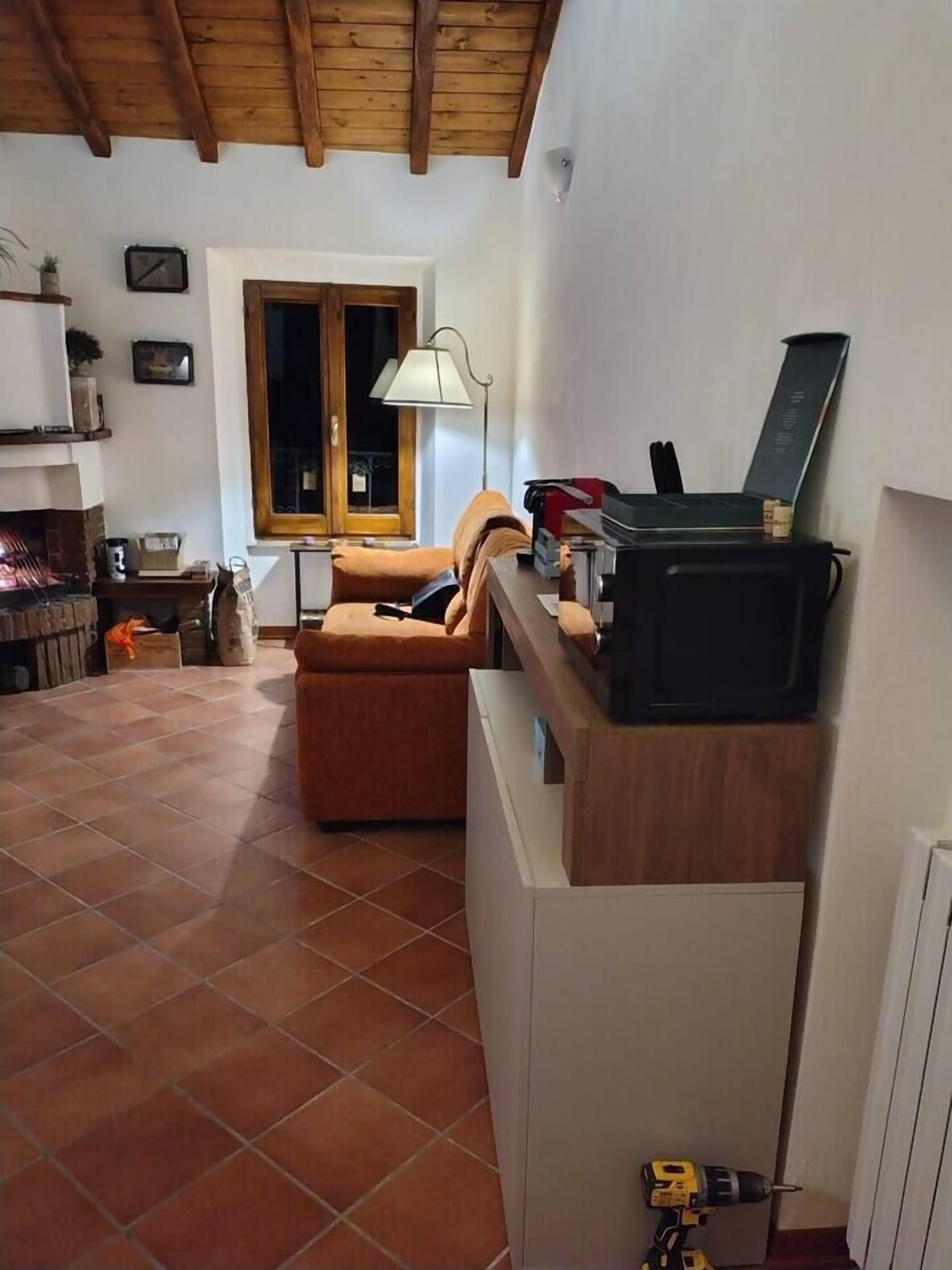 Et køkken med træbordplade, mikroovn og lampe.