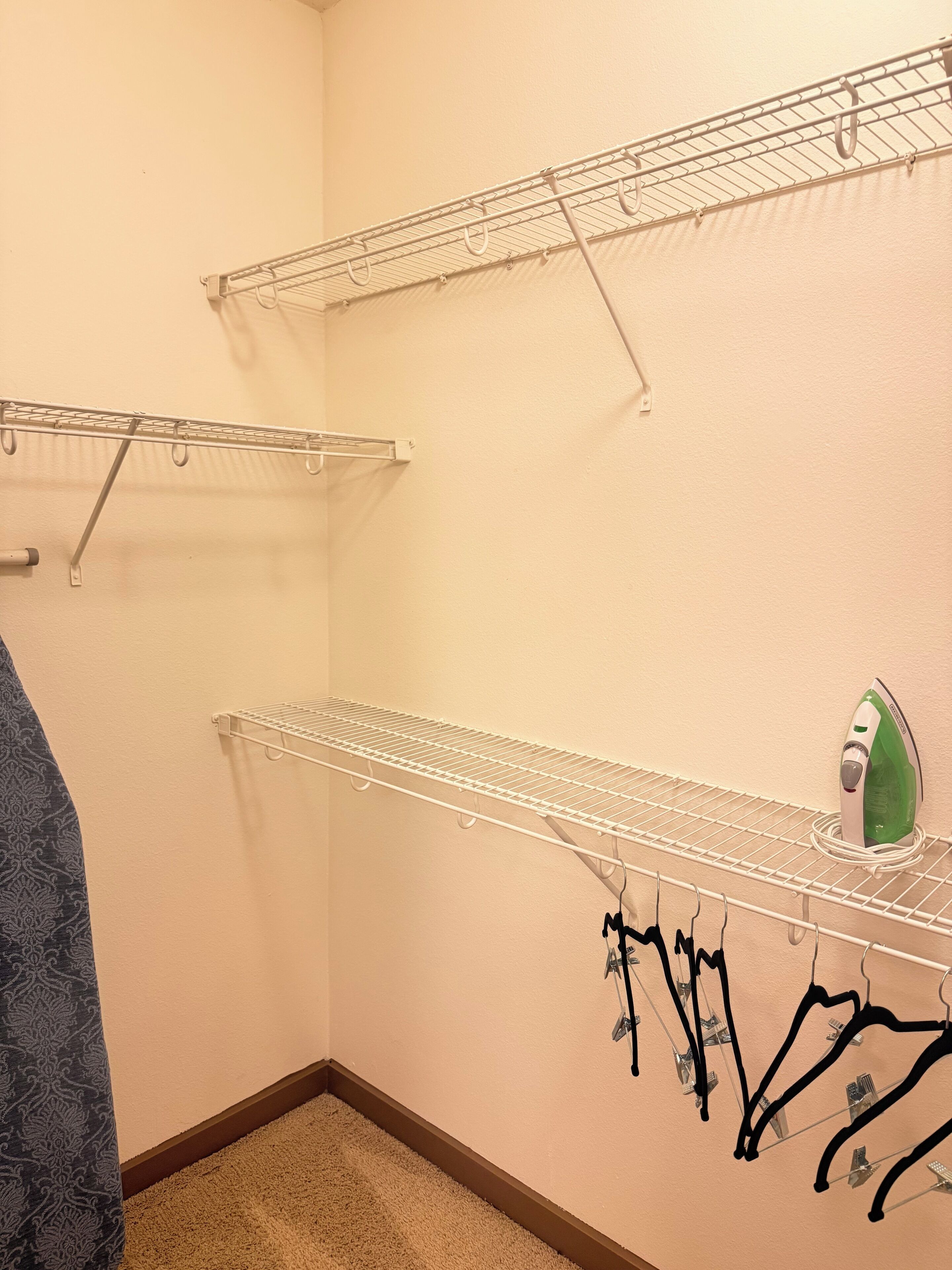 A laundry area with metal drying racks and a green iron.