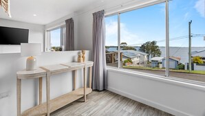 A modern kitchen with a large window, a flat-screen TV, and a wooden console table. - Lakeside 2-bed Retreat With Sunny Balcony (Buff Point)