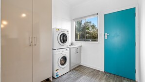 A compact laundry room with a washing machine, a dryer, and a window. - Lakeside 2-bed Retreat With Sunny Balcony (Buff Point)