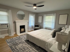 A bedroom with a bed, a fireplace, a ceiling fan, and a window with curtains. - 3BR Family and Pet-Friendly College Hill Home • Walk to Wesley (Wichita)