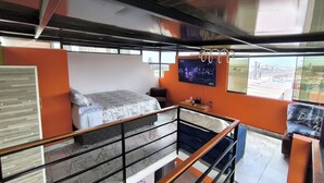 Een moderne hotelkamer met een bed, een televisie, een bureau en een balkon met uitzicht.