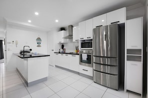 Uma cozinha moderna com armários brancos, eletrodomésticos de aço inoxidável e uma ilha central.