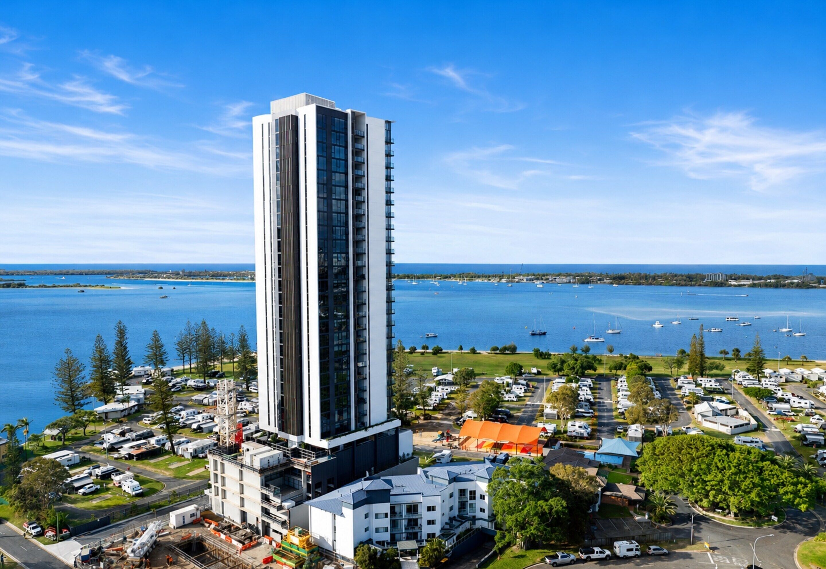 Un hotel alto dal design moderno, situato vicino a un porto con imbarcazioni.