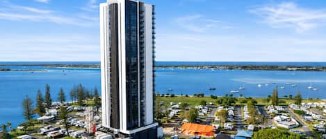 A tall hotel with a modern design, located near a marina with boats.