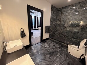 A modern bathroom with a marble floor, a white bathtub, a toilet, and a black vanity. - Luxury 2 bedroom penthouse in Mount Vernon, Baltimore MD (Baltimore)