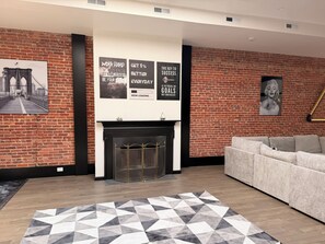 Ein modernes Wohnzimmer mit Backsteinwand, Kamin, einer Couch und motivierenden Postern.