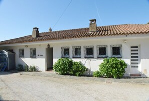 Ein weißes Gebäude mit einem Ziegeldach, zahlreichen Fenstern mit Metallgitter und zwei Schornsteinen.