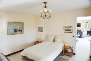Ein Schlafzimmer mit einem Bett, einer Chandelier, Nachttischen und gerahmten Bildern an den Wänden.