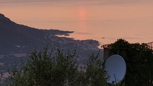 Een zonsondergang boven een rustig wateroppervlak, met een berg op de achtergrond.