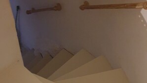 Een trap met een leuning en een witte muur.