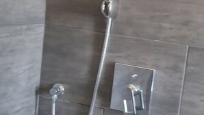 Een douche met een handdouche en een bediening aan de muur.
