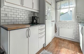 A kitchen with white cabinets, a wooden countertop, a refrigerator, a window with a view, and a radiator. - 4 bedroom amazing home in Villshärad (Villshärad)