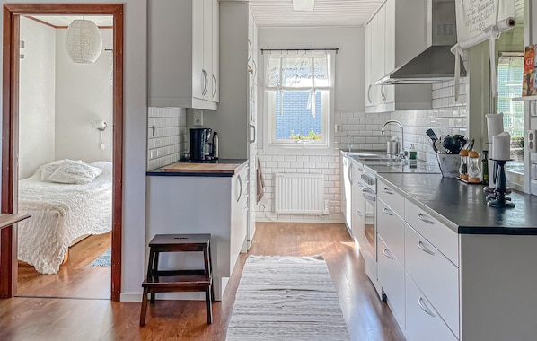 A compact kitchen with white cabinets, a wooden countertop, and a window with blue shutters. - 4 bedroom amazing home in Villshärad (Villshärad)