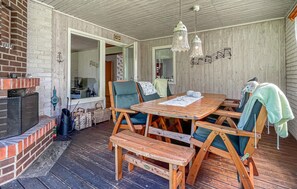 A covered patio with a wooden table, chairs, a bench, a brick fireplace, and a hanging light fixture. - 4 bedroom amazing home in Villshärad (Villshärad)
