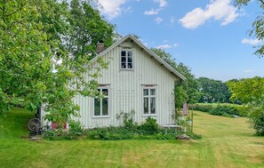A white wooden house with a gabled roof, surrounded by a well-maintained lawn and trees. - 3 bedroom amazing home in Långås (Långås)