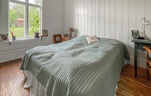 A room with a bed, a window with a view of greenery, a desk with a lamp, and a chair. - 3 bedroom amazing home in Långås (Långås)