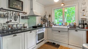 Una cocina con gabinetes blancos, estufa, lavaplatos y diferentes utensilios de cocina.