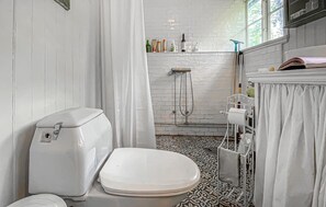 A bathroom with a white toilet, a shower, and a patterned floor. - 3 bedroom amazing home in Långås (Långås)