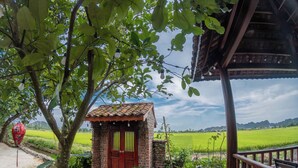 A rustic brick house with a tiled roof, a wooden door, and a small porch with a railing.
