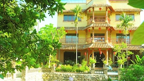 A multi-story building with balconies, a stone wall, and a water feature.
