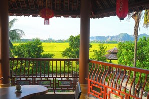 Ein Balkon mit Blick auf ein grünes Feld und ein traditionelles Gebäude in der Ferne.