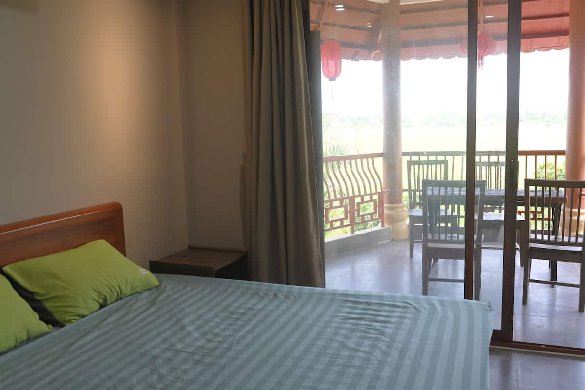 Un dormitorio con cama, mesita de noche y vistas a un balcón exterior con sillas y una mesa.