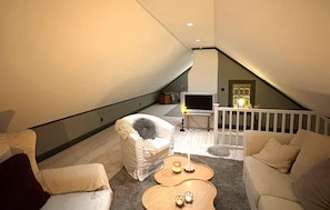 Ein gemütliches Schlafzimmer im Loft-Stil mit schrägem Dach, einem Fernseher und einer Treppe zu einer erhöhten Ebene.