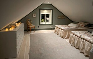 A small attic bedroom with a sloped ceiling, a window with a view, a chair, and two beds. - 2 bedroom amazing home in Vaggeryd (Vaggeryd)