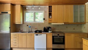 Une cuisine dotée de meubles en bois, d’un réfrigérateur en acier inoxydable, d’un lave-vaisselle, d’une machine à café et d’une cuisinière.