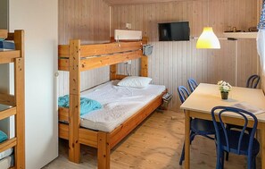 Ein Stockbett mit Fernseher und Lampe, ein Tisch mit Stühlen und eine kleine Pflanze.