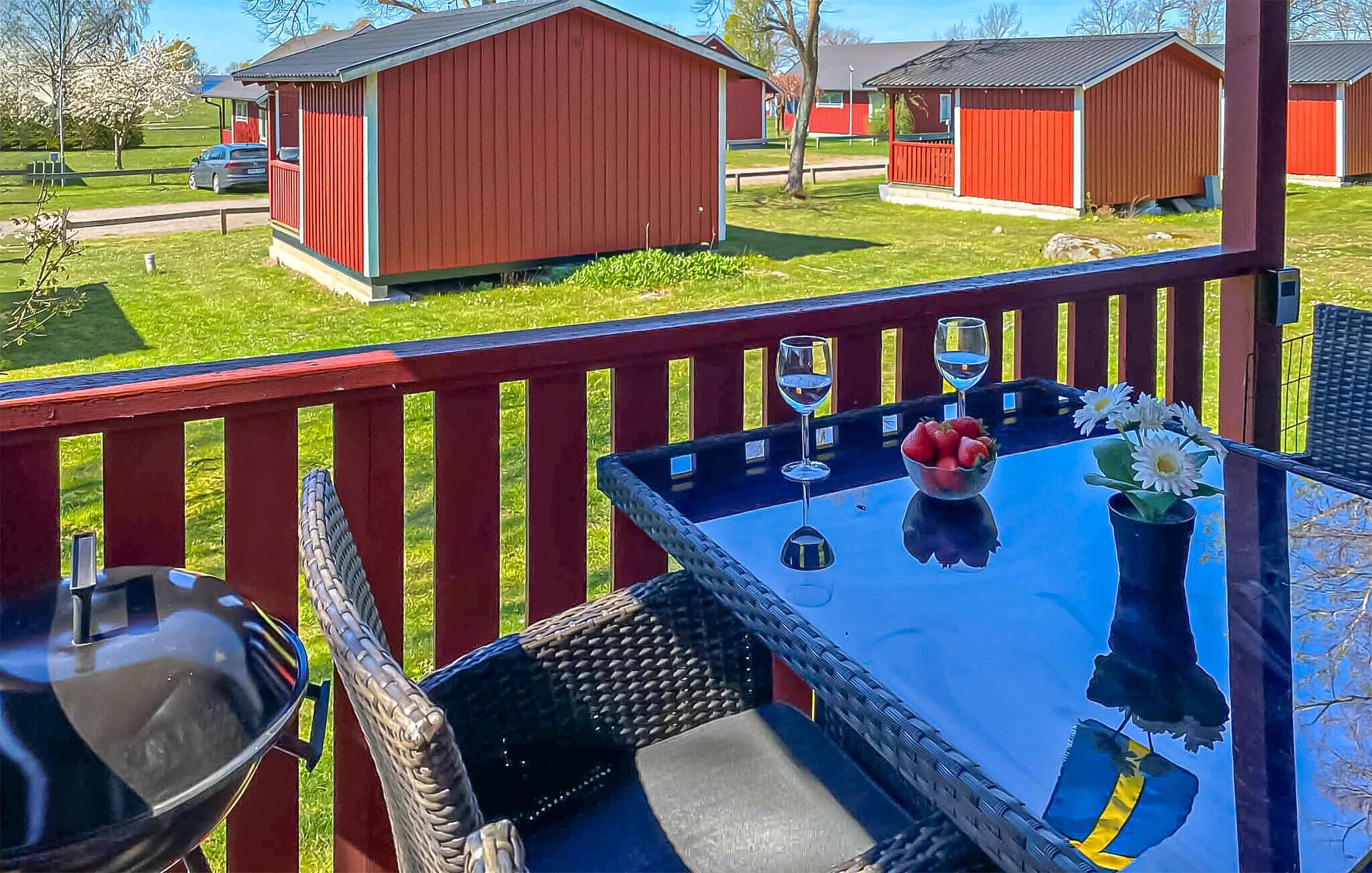 A patio with a table, chairs, a grill, and a view of red buildings in the background.