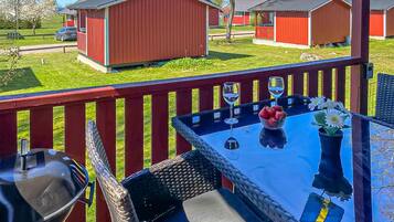 A patio with a table, chairs, a grill, and a view of red buildings in the background.