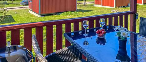 A patio with a table, chairs, a grill, and a view of red buildings in the background.