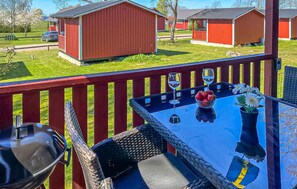 Eine Terrasse mit Tisch, Stühlen, einem Grill und Blick auf rote Gebäude im Hintergrund.