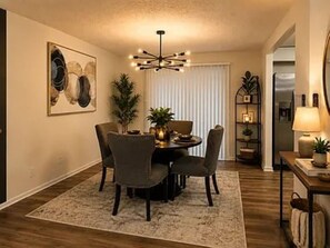 A dining area with a round table, chairs, a chandelier, and a plant. - Beautiful 3-bedroom house in tranquil Lithonia perfect for relaxing stays (Lithonia)