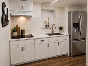 A modern kitchen with white cabinetry, a stainless steel refrigerator, and a built-in oven. - Beautiful 3-bedroom house in tranquil Lithonia perfect for relaxing stays (Lithonia)