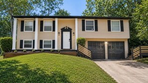 A two-story building with a front entrance, a garage, and a well-maintained lawn. - Beautiful 3-bedroom house in tranquil Lithonia perfect for relaxing stays (Lithonia)
