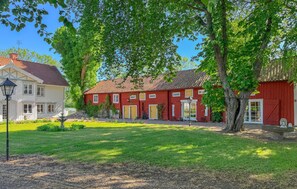 A red building with a white facade, a well-maintained lawn, and a lamppost. - 1 bedroom amazing home in ödeshög (Ödeshög)