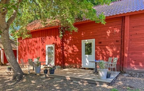 A red wooden building with a porch, potted plants, and outdoor furniture. - 1 bedroom amazing home in ödeshög (Ödeshög)