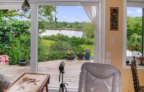 Una habitación con vistas a un lago, un telescopio y una silla.